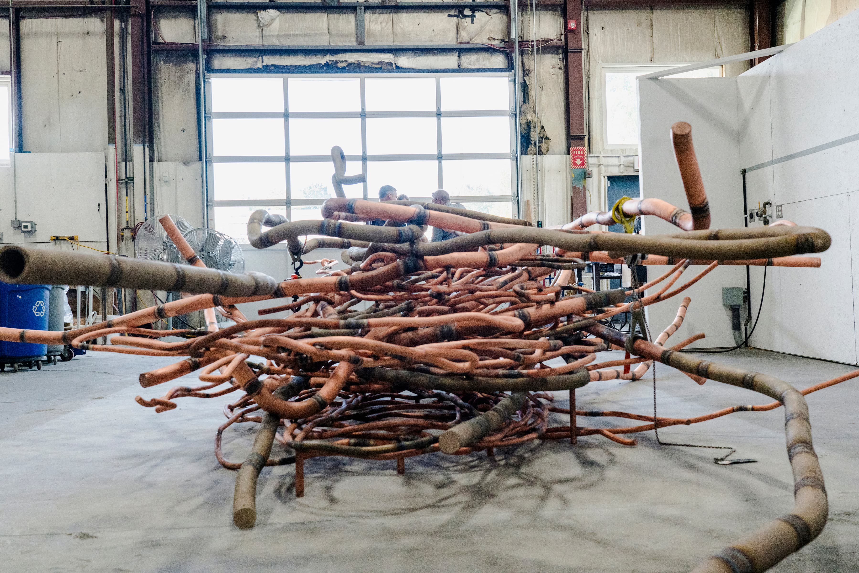 A color image of a copper rod sculpture in an industrial space.